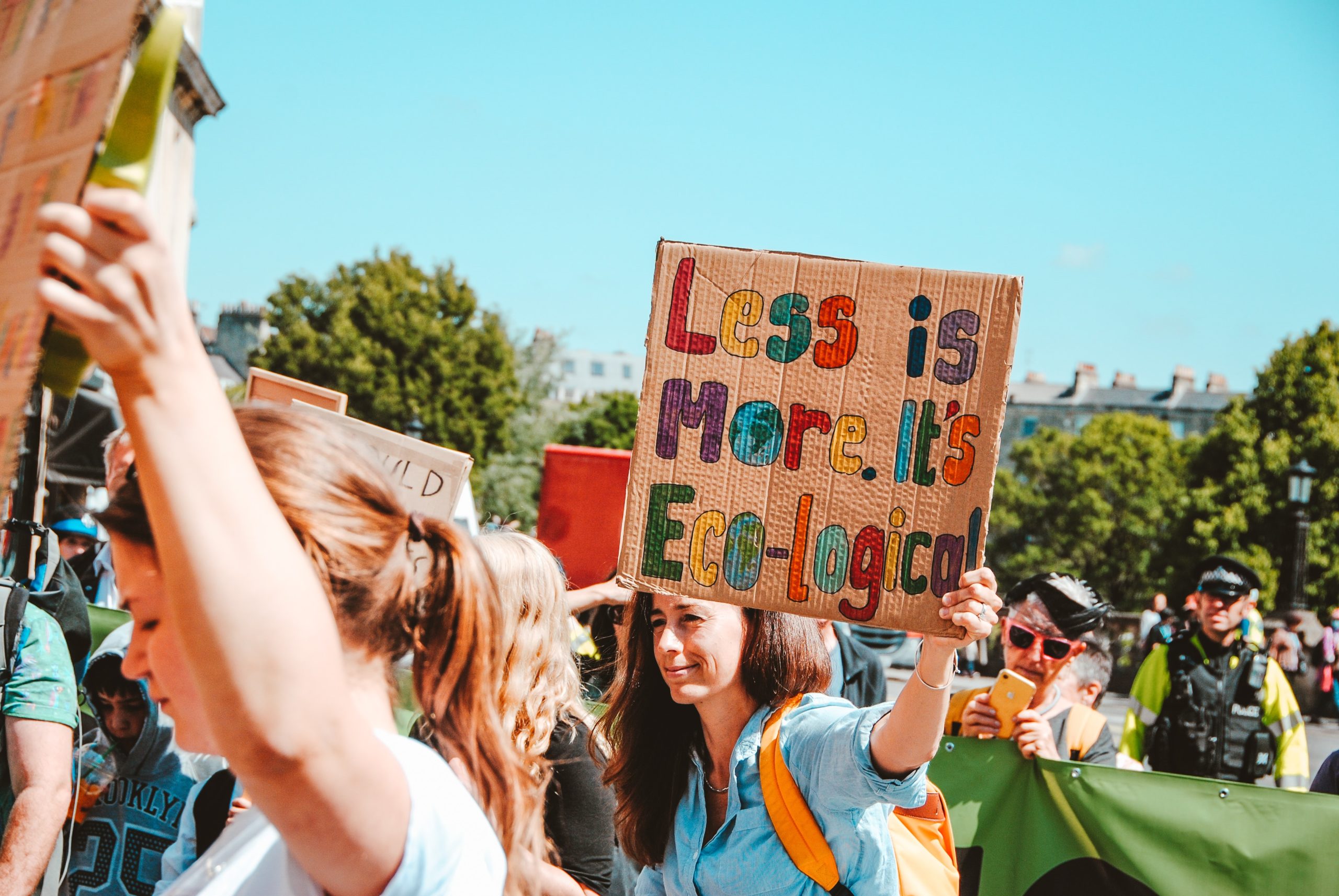 Protestor woman holding up the sign Less is More Ecological